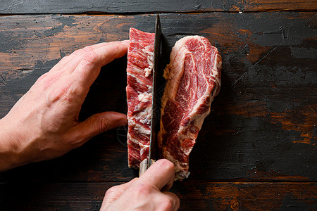 男人用切肉刀切肉 有机牛肉 在工作印章 在深色木板背景上 文本空间背景