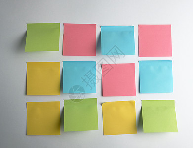 粉红色 蓝色 绿色纸贴在白色背景上黄色备忘录笔记贴纸木板记忆邮政软垫标签床单背景图片
