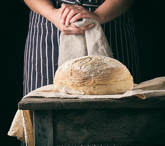 手面包穿着围裙的女人拿着灰色纸巾和圆面包背景