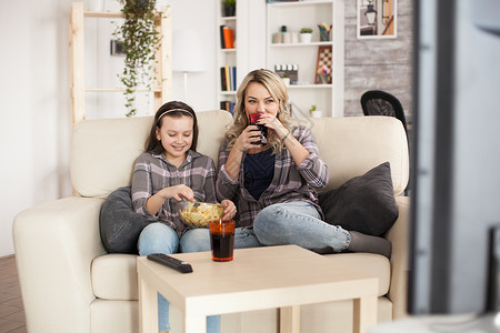 母亲和女儿在起居室监视器苏打房间情感长椅小吃家庭展示筹码娱乐背景图片