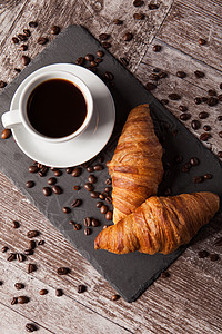 一杯咖啡 用新鲜的羊角面包豆铺开咖啡豆早餐面包屑食物小吃甜点糕点毛巾黄油金子木板背景图片