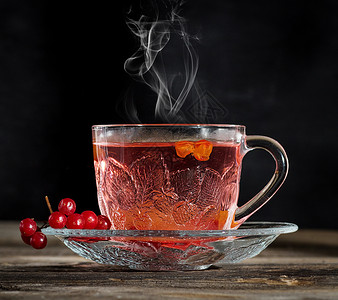在透明杯子里的热生茶荚蒾飞碟预防药品浆果玻璃蒸汽饮料桌子液体背景图片