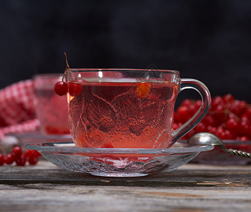 在透明杯子里的热生茶 手柄和碟子水果勺子飞碟荚蒾玻璃食物芳香木头浆果桌子背景图片
