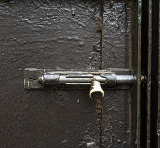 深绿色金属门上的旧铁锁背景图片