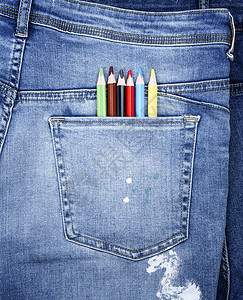 蓝色牛仔裤后袋中的彩色铅笔红色创造力蜡笔绘画白色教育织物口袋黄色背景图片