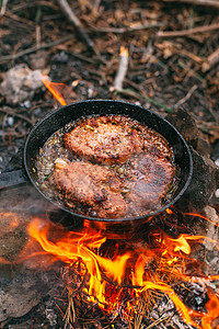 炭锅与红菜一起在露天着火的锅里煎肉 将牛排放在锅里旅游餐厅油炸菜单烹饪胡椒食物森林蔬菜香料背景