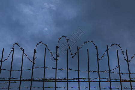 有刺带铁丝网的栅栏夜空安全监狱边界金属高清图片