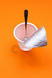 塑料勺子橙色背景的勺子空清酸奶杯薄片早餐塑料牛奶厨房橙子食物奶油饮食奶制品背景