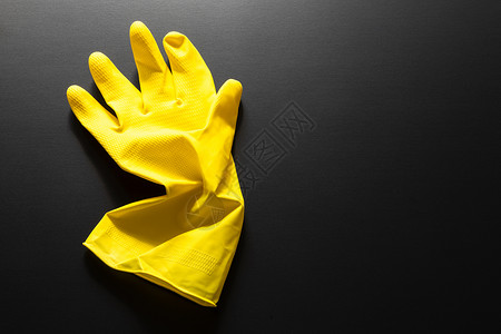 黑色手套在黑色背景上隔离的黄色橡胶手套用具橡皮打扫手指背景