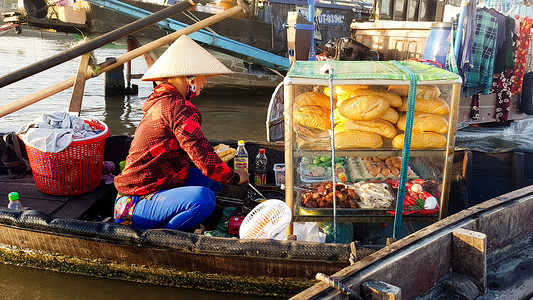 芹苴桥一个街头食品销售商 在木船上出售banh mi背景