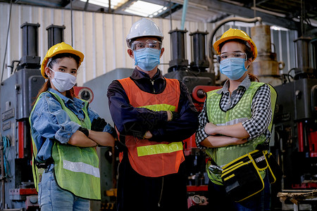 一群戴着卫生面具的男女工人在工厂区自信地行动高清图片