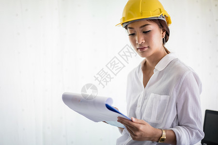 亚洲女性工程检查 工作和持有蓝色桌子经理安全帽笔记本安全女士商业蓝图人士团队背景图片