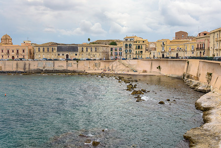 Ortygia岛滨水面 小石子海滩房子天空遗产建筑学海岸长廊海岸线城市脊柱蓝色背景图片