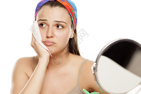在镜子前擦着湿巾的疲累和悲伤的年轻女子女性去除剂纸巾卫生化妆品女孩压力美容背景图片