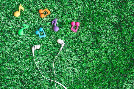 绿色草原上耳机的顶端视图工具收音机立体声场地音乐草地派对笔记歌曲娱乐背景图片