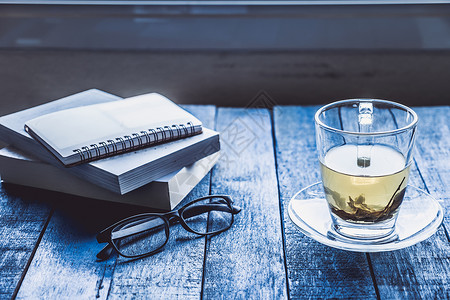 杯茶 木制桌上有书和眼镜桌子飞碟玻璃杯子蓝色笔记本时间背景图片