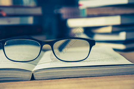 在木桌 软焦点 旧音上 贴近有眼镜的开放书知识闲暇智慧故事学习桌子学校木头教科书考试背景图片