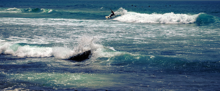 太阳光灯冲浪者乘着浮板蓝海水随心所欲蓝色男人海浪假期旅行运动乐趣行动设施冲浪背景图片
