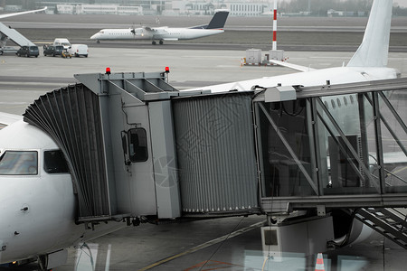 机场上的飞机连接到门套 飞机和套筒 机场门口供乘客登机假期跑道旅行燃料方法服务建筑袖子商业天空背景