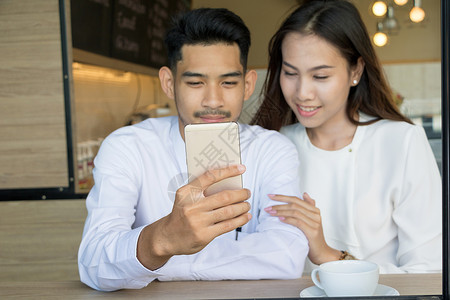 在咖啡店相爱的亚洲年轻夫妇咖啡享受快乐女士时间药片电话女性男人男朋友背景图片