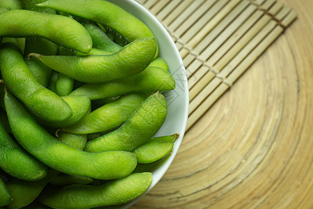 在煮沸前毛豆Edamame在白碗中展示食物内容的顶端视图图像蔬菜桌子大豆营养毛豆饮食绿色美食小吃豆类背景