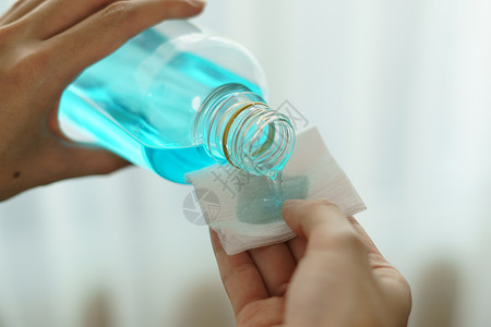 将乙基酒精从瓶子中倒入棉花片 以备冠状液体消毒剂卫生棉布清洁工乙醇塑料治疗伤口药品背景图片