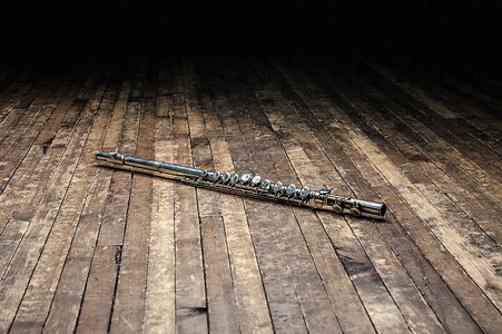 银金银金属笛子在黑暗中的木制舞台上背景图片