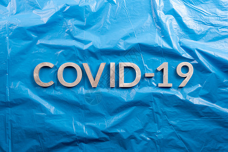 CCOVID-19用铝字母拼贴在压成蓝色塑料胶片背景上 以平面结构组成 直接高于视线背景图片