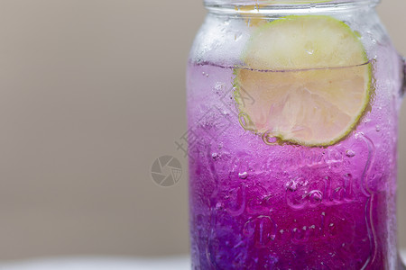 鲜紫蝴蝶梨或蓝豌豆花和柠檬汁柠檬木头蓝色玻璃花园果汁饮料茶点热带植物群背景图片