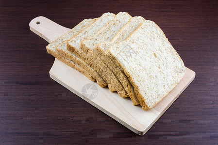 在购物木上切掉的全麦小麦面包小麦面包黑色木板木头生活白色粮食食物农业背景图片