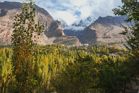 卡里马巴德在洪扎山谷的山顶上铺满云彩的绿林背景