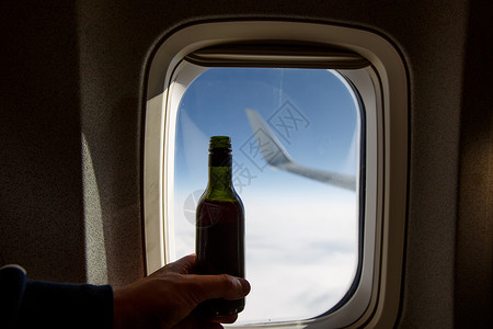 在门洞对面一瓶酒 飞机上酒精味的瓶子天空产品玻璃奢华旅行饮料喷射托盘小样运输背景图片