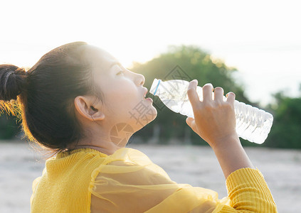 亚洲妇女从塑料瓶中饮用纯水和轻光i背景图片