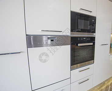 在豪华公寓的现代厨房设备装饰白色炊具烤箱橱柜设计家具器具电烤箱背景图片