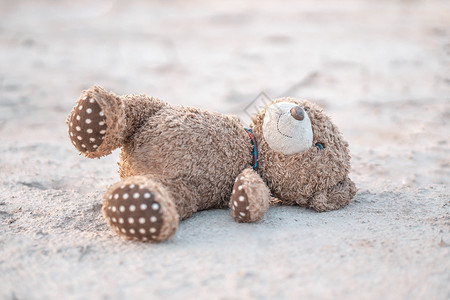 闭紧泰迪熊玩具 独自躺在地上毛皮棕色童年损失孤独地面动物孩子丢弃礼物背景图片