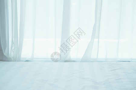 白色床边的白色床 透过窗口 curtai 可以看到窗帘床垫家具房间纺织品床单寝具窗户酒店卧室背景图片