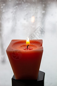 冬天晚上 烛光在寒冷的窗口附近燃烧着蜡烛窗台毛线建筑学茶色火焰紫色房子玻璃温暖磨砂背景图片