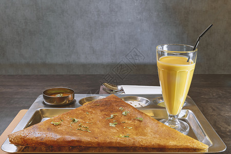 萨拉凯印度素食煎饼 配有芒果汁 在偷的盘子上和几类酱汁背景