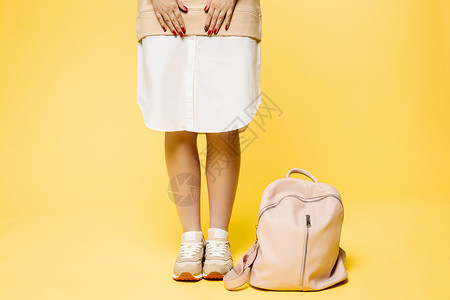 新款潮包穿着时髦的米衣的女人 在皮包旁边站着魅力冒充地面裙子褐色美甲皮革隐姓埋名女性指甲背景