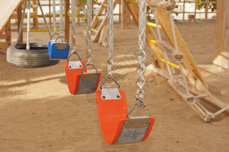 儿童游戏区的摇摆玩具乐趣框架公园孩子们橙子塑料游乐蓝色操场背景图片