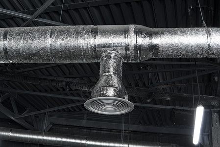 冷气机大型建筑物天花板上的通风系统 新建筑天花板上悬挂着银色绝缘材料的通风管金属工程安装空气仓库管子办公室空调工厂建筑学背景