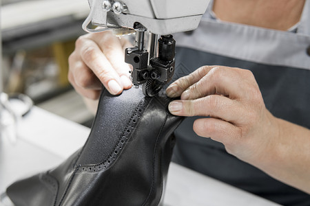 皮革车间的缝纫机在用手处理鞋子的皮革细节 在鞋厂 老妇人的手拿着缝纫机制造业缝纫工人工厂水牛工作奶牛生产工艺裁缝背景图片