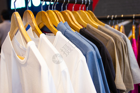 挂在衣架上的多彩色T恤 在百货商店出售服装衬衫壁橱织物衣服架子棉布店铺裙子男人背景图片