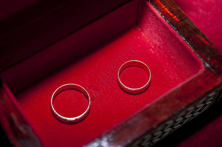 在盒子里对着结婚戒指乐队婚姻首饰天鹅绒金子宏观圆圈夫妻木头红色背景图片