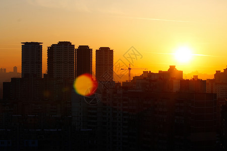 城市背景的橙色日落 骗人的轮廓蓝色橙子阳光日出耀斑天空摩天大楼建筑坡度太阳光图片