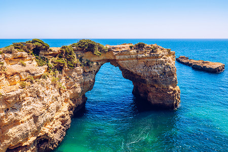 海洋上方的自然拱门 葡萄牙阿尔加夫 阿尔班代拉阿科悬崖海岸线观光岩层石头海景海滩海鸥岩石沙滩背景