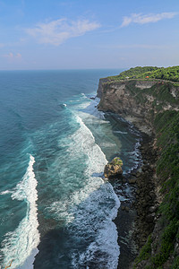 印度尼西亚巴厘岛的乌鲁瓦图悬崖与凉亭和蓝色大海的景色 寺的美丽风景 白天有五颜六色的鲜花前景 高悬崖风景秀丽的沿海景观太阳海滩日背景图片