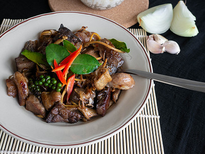 炸猪内脏的名字是 Phad cha 泰国菜 配料是猪肉馅辣椒 Krachai 大蒜洋葱和 Kaffir 石灰叶 杯子里的米饭 背背景图片