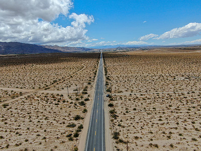 美国Joshua树公园无尽的沙漠直成灰尘的沥青路空中景象岩石汽车天空空路风景蓝色爬坡假期孤独长路背景图片