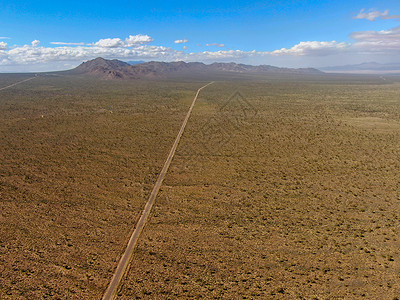 美国Joshua树公园无尽的沙漠直成灰尘的沥青路空中景象旅行公园运动编队孤独汽车荒野蓝色天空空路背景图片